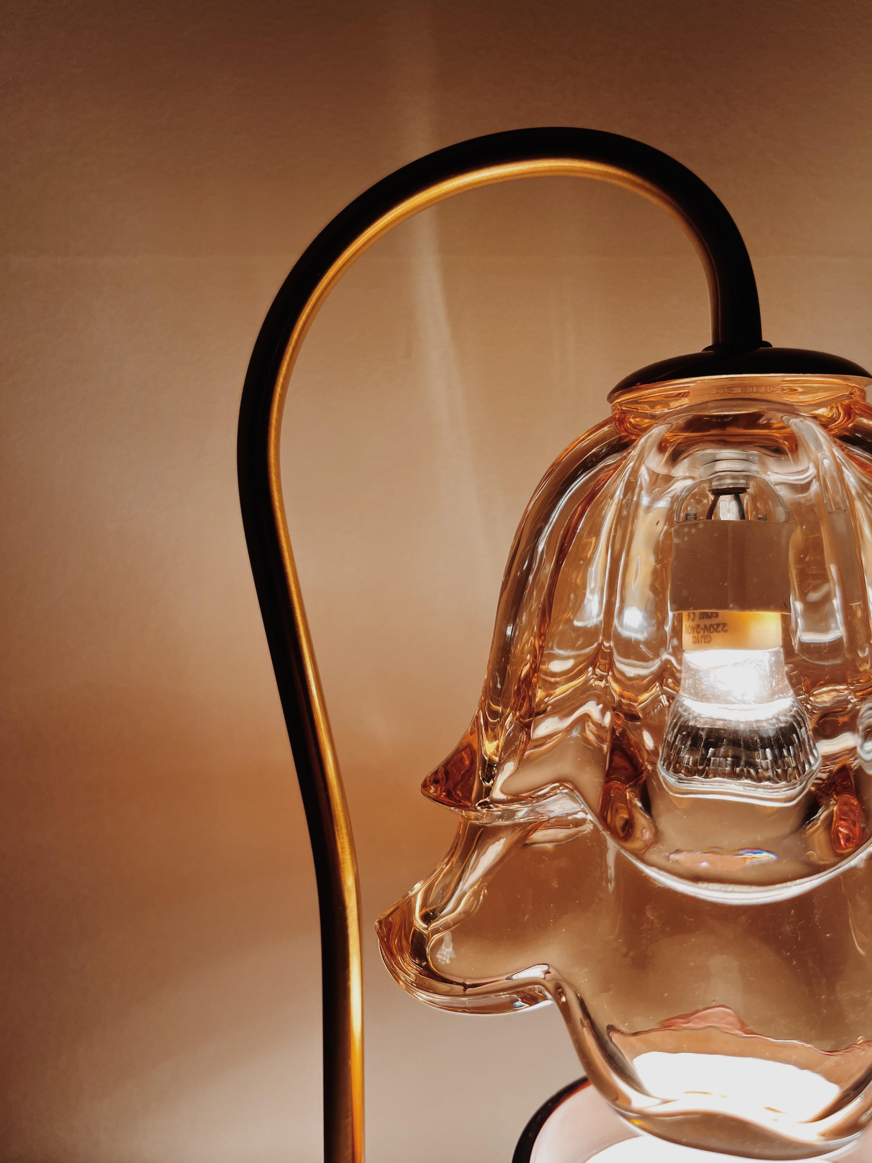 Auren Bloom Candle Warmer Close-up. Showcasing it's flower-shaped glass shade with elegant curves and soft lighting, highlighting the delicate craftsmanship and warm glow ideal for cozy home decor