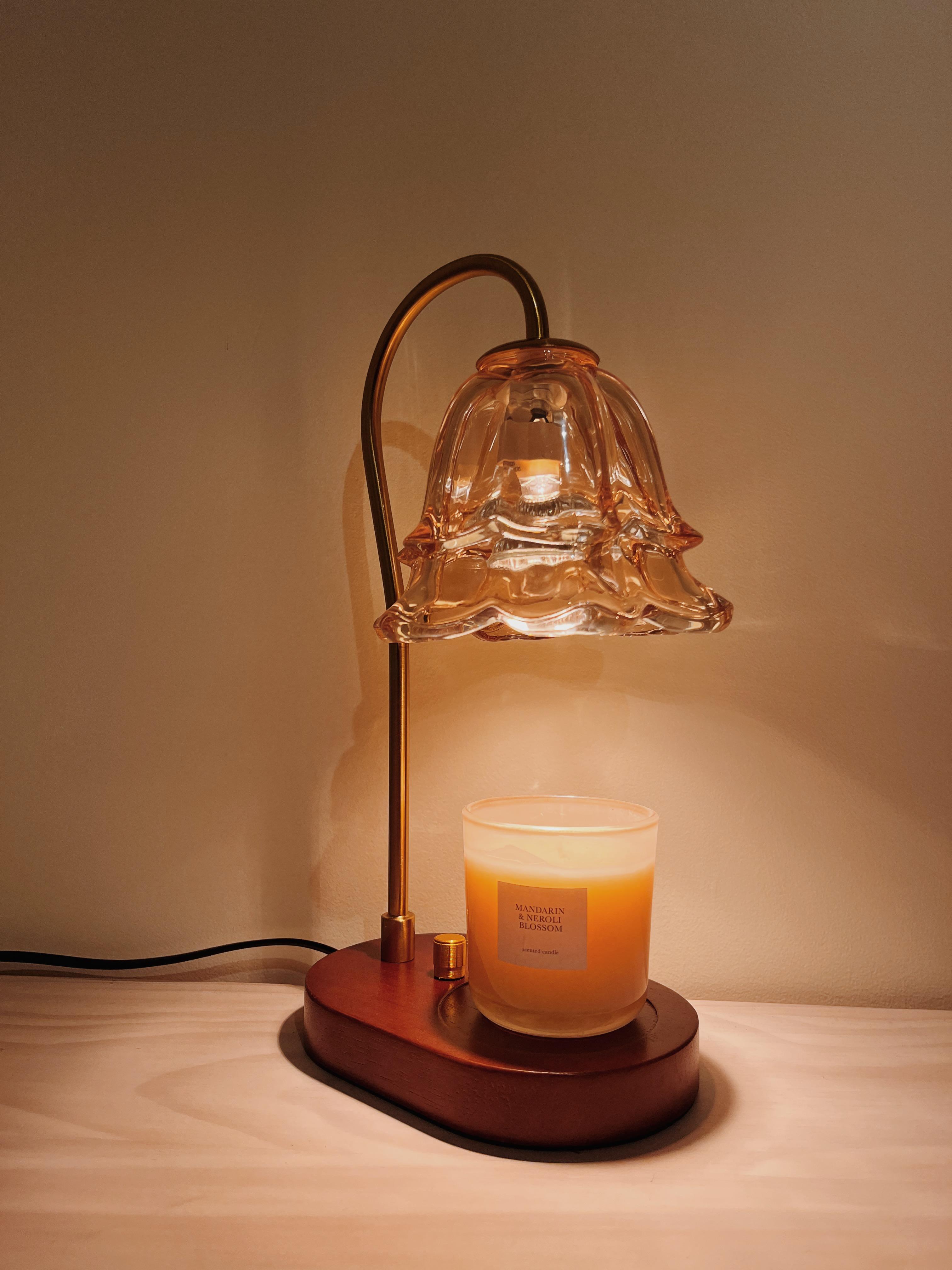 Auren Bloom candle warmer lamp with a flower shaped glass shade melting a Mandarin & Neroli Blossom candle on a wooden base, adding warmth, charm and vintage aesthetic to any home.