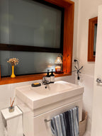 Auren Bloom Candle Warmer within a sleek, minimalist bathroom styled with soft ambient lighting from a candle warmer placed on the windowsill, illuminating a soothing scented candle and elevating the evening self-care routine with a warm, peaceful glow.