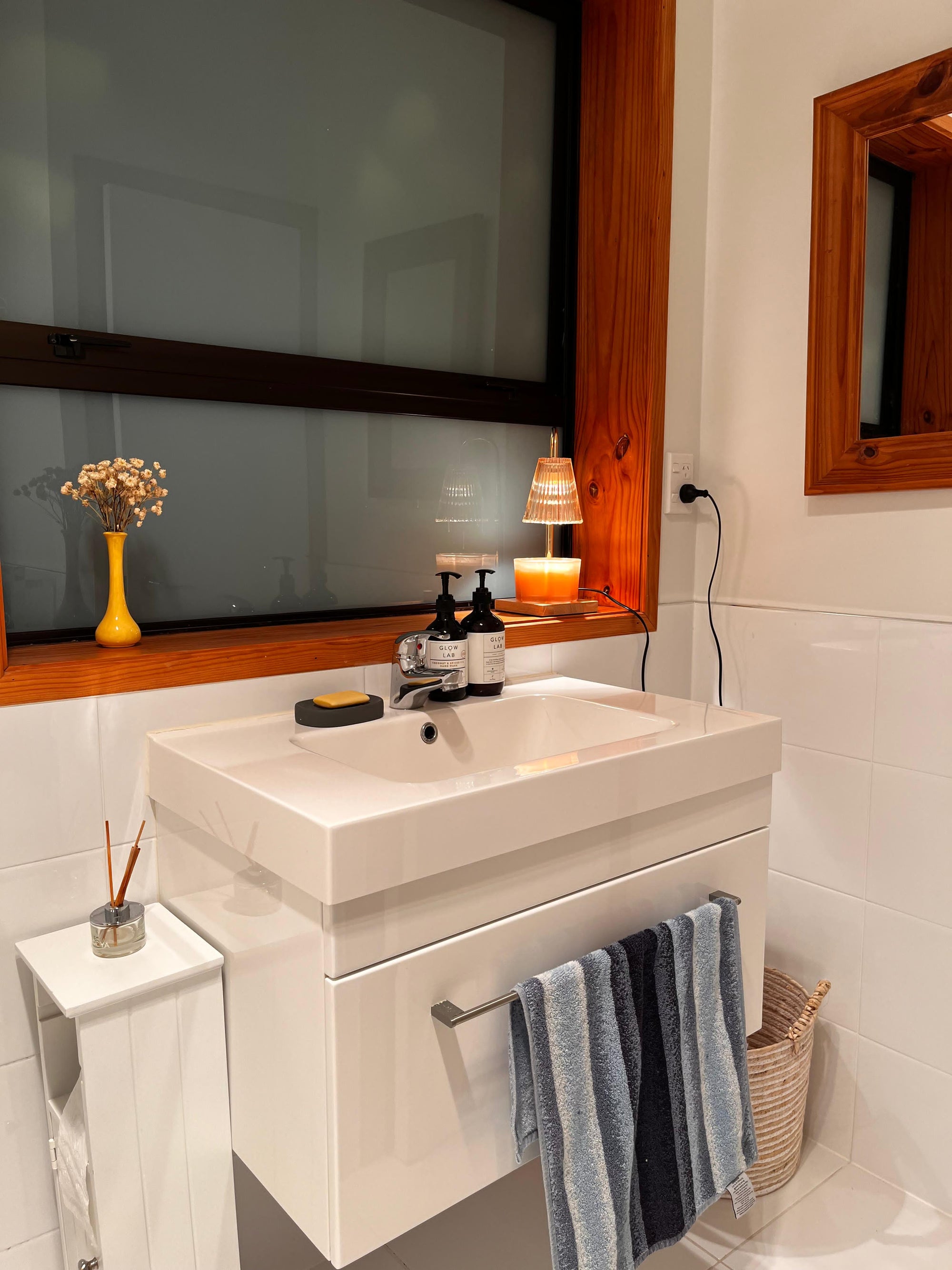  Auren Elegance Candle Warmer in a modern bathroom sink setup with soft, ambient lighting from a stylish candle warmer glowing atop the windowsill, gently warming a creamy-toned candle—creating a spa-like, calming atmosphere perfect for evening wind-down routines.