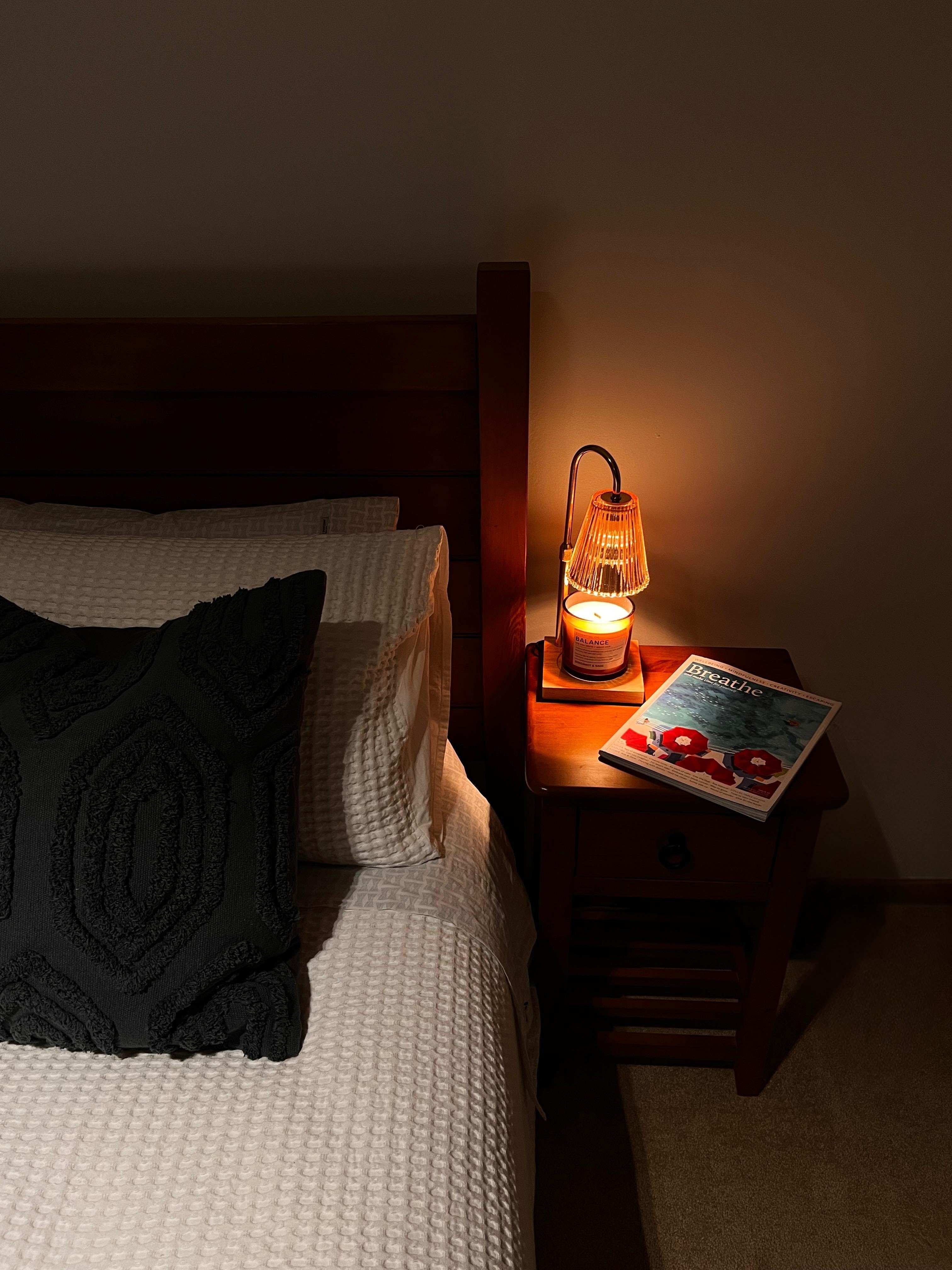 Auren Elegance Candle Warmer glowing on a wooden bedside table